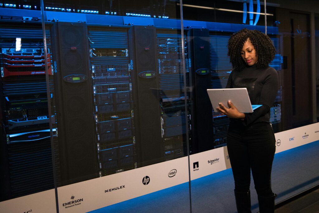 pexels-photo-1181354-1181354 A female engineer using a laptop while monitoring data servers in a modern server room.